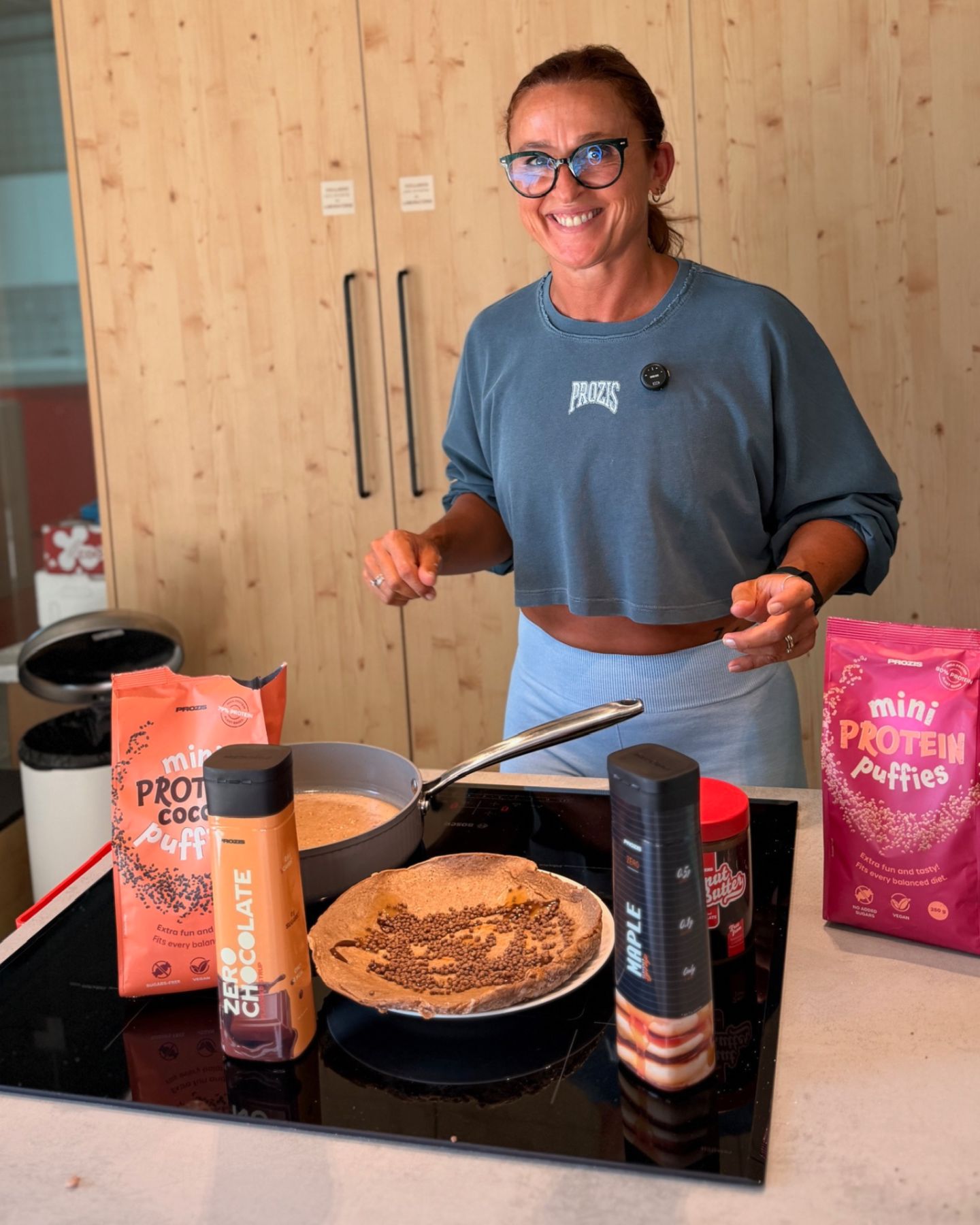 A coach prepara uma panqueca proteica na cozinha.